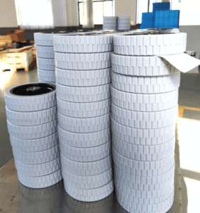 Floor scrubber gray roller wheels, multiple stacks of 200×50 mm wheels with textured tread, arranged in a warehouse setting.