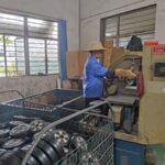 Worker operating machinery, rubber wheel finishing, factory production, quality control in industrial workshop.