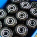 Industrial rubber wheels in blue storage bin, black tread with metal core, organized for warehouse or production use.