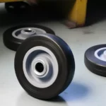 Black rubber wheel with grey core, material handling caster wheel, heavy-duty floor application, smooth rolling design.